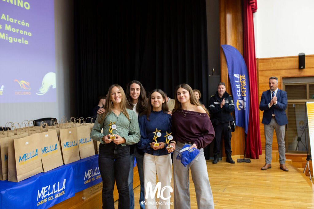 Cuatro jóvenes ciclistas posando con trofeos en la Gala de Ciclismo de Melilla
