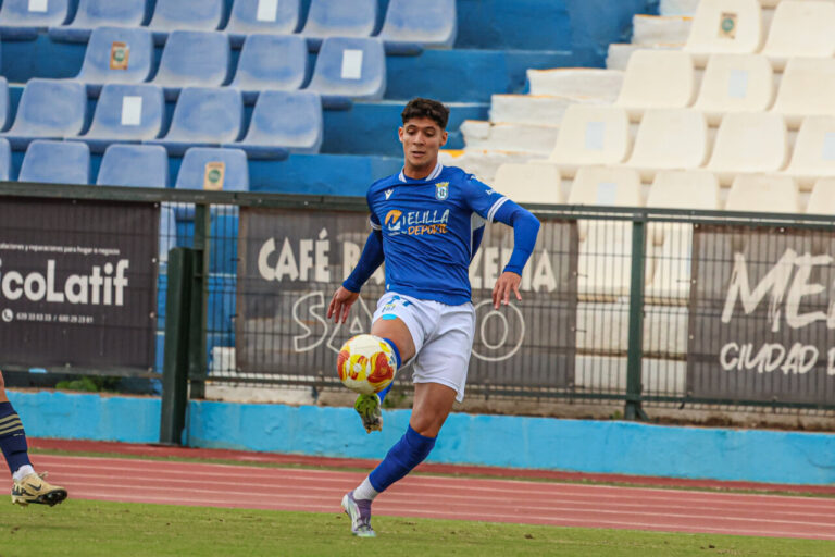 Jugador de la U.D. Melilla controlando el balón en un partido de fútbol