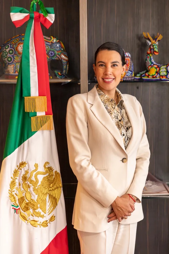 Josefina Rodríguez posando junto a la bandera de México en un evento