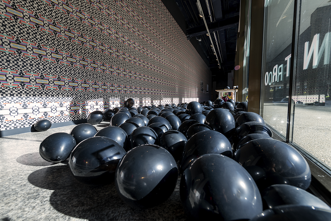 Instalación de arte contemporáneo con formas esféricas negras en un espacio moderno.
