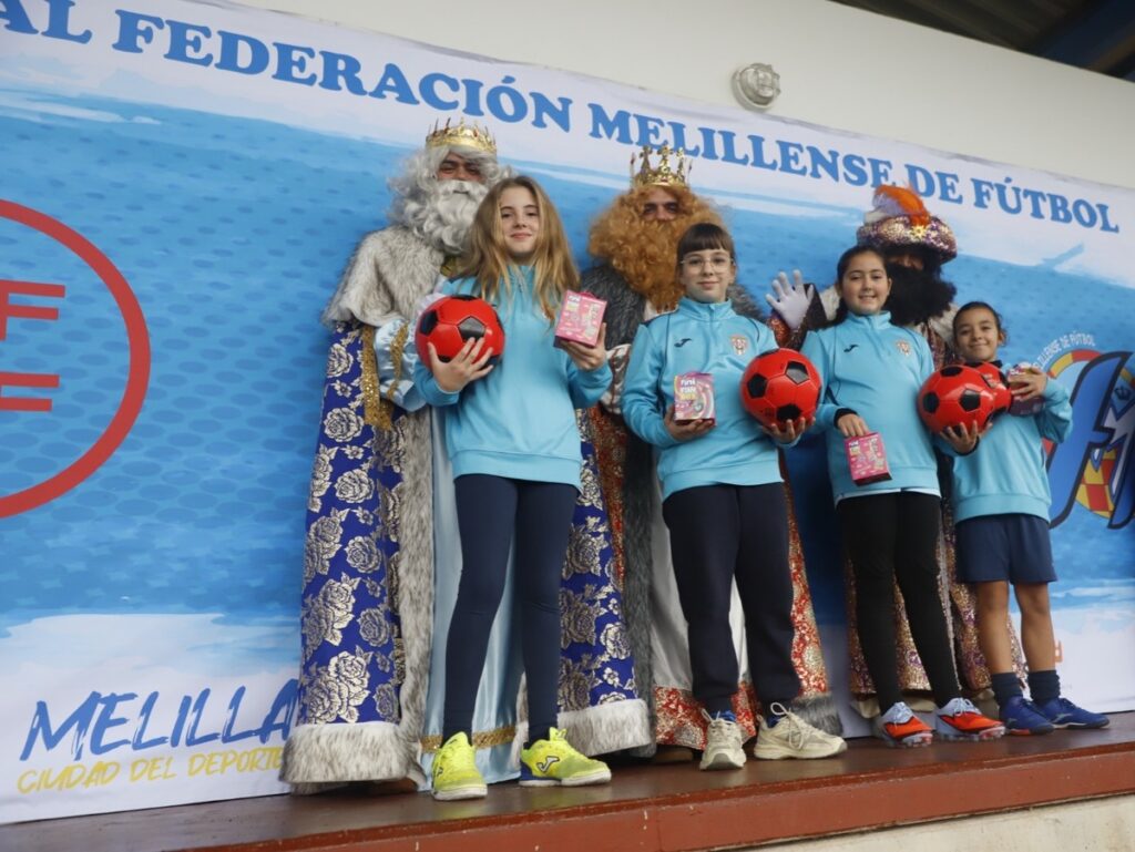 Niños recibiendo regalos de los Reyes Magos en un evento deportivo