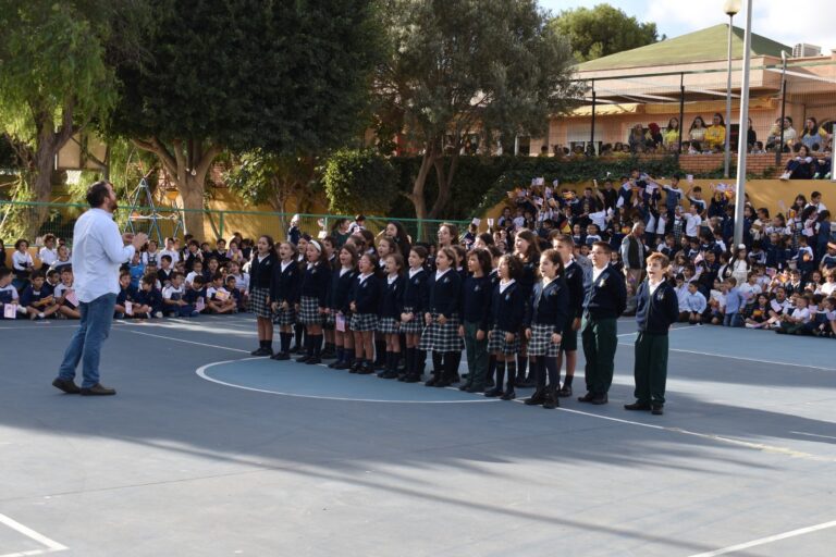 Grupo de niños cantando en una actuación escolar al aire libre