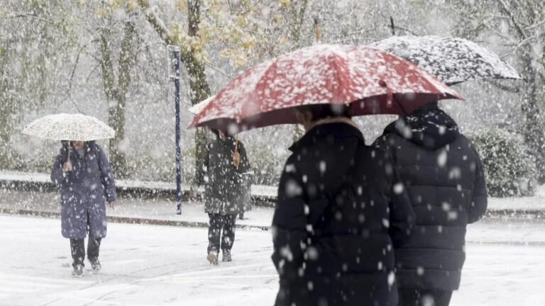 Personas caminando bajo la nieve con paraguas en un día de Reyes