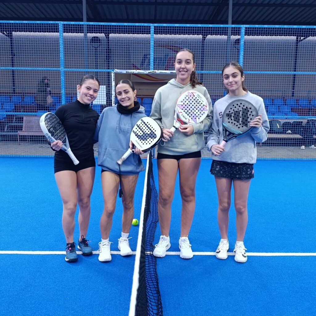 Cuatro jóvenes jugadoras de pádel posando en la cancha