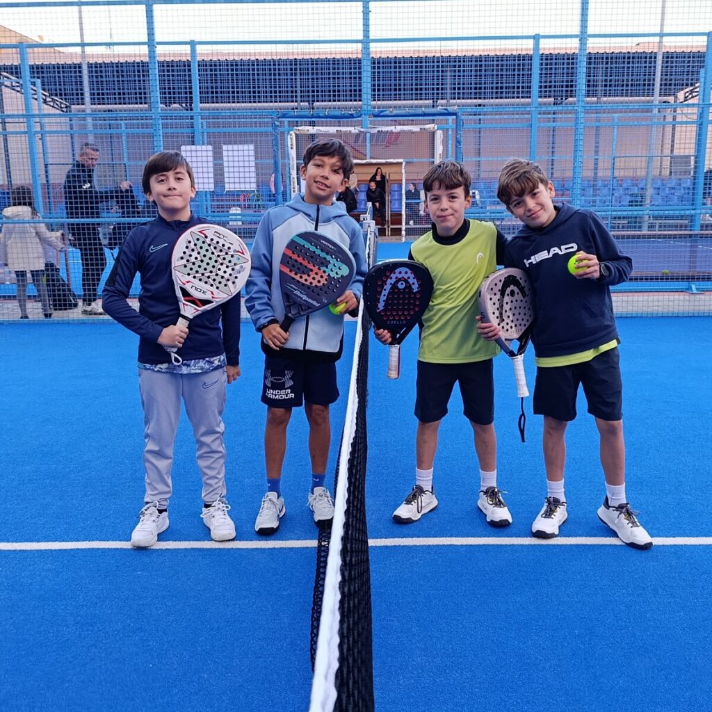 Cuatro jóvenes jugadores de pádel posando en la cancha