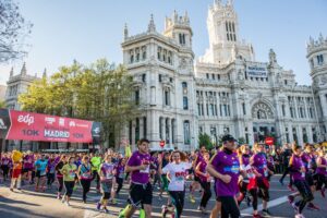 Corredores participando en la carrera de Madrid 2026 con edificio histórico al fondo