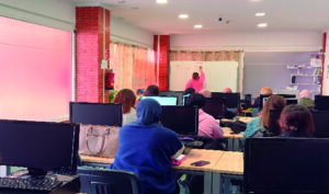 Clase de educación para mayores de 18 años en un aula con computadoras.