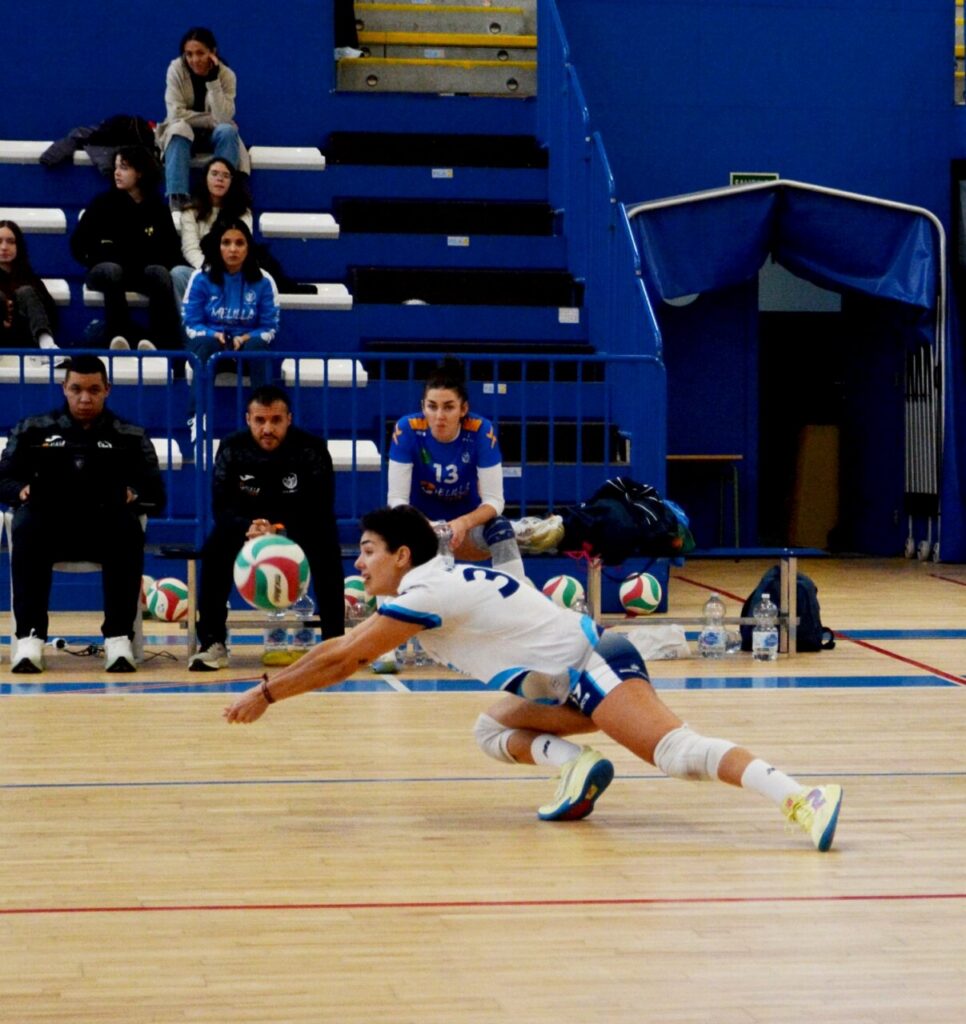 Jugadora del Club Voleibol Melilla se lanza para recibir el balón durante un partido.