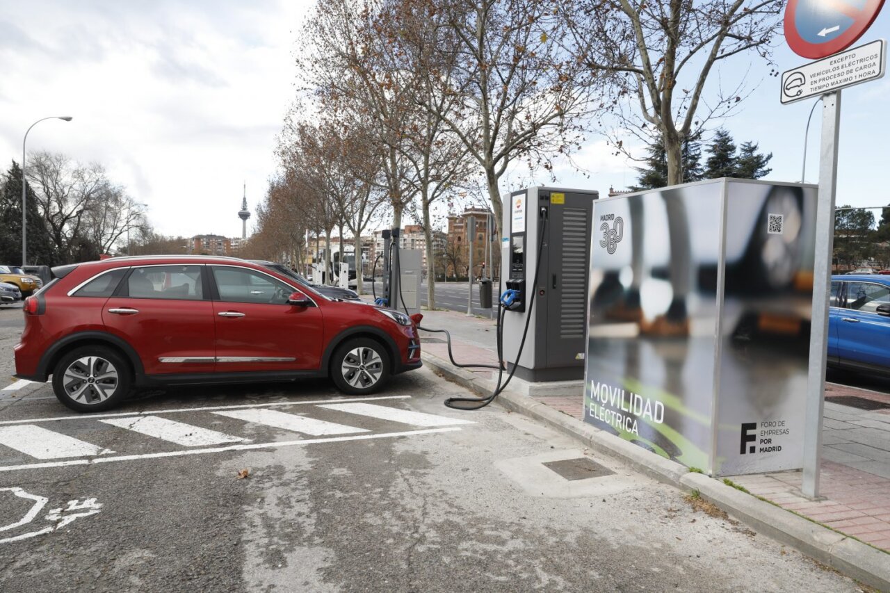 Coche eléctrico rojo cargando en estación de carga en Madrid