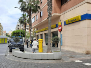 Oficina de Correos con personas y vehículos en la calle