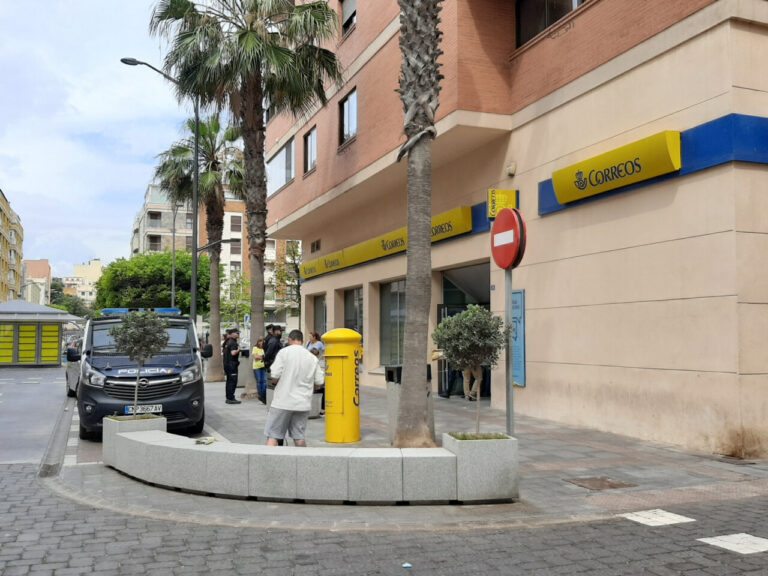 Oficina de Correos con personas y vehículos en la calle