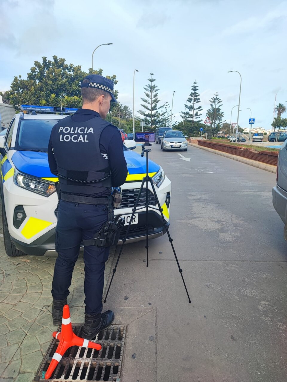 Agente de policía local usando un dispositivo con trípode en control de tráfico