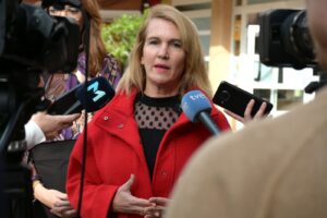Mujer con abrigo rojo hablando a la prensa