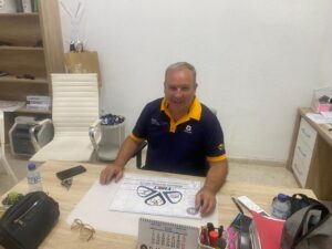 Hombre sonriente en una oficina con documentos de triatlón