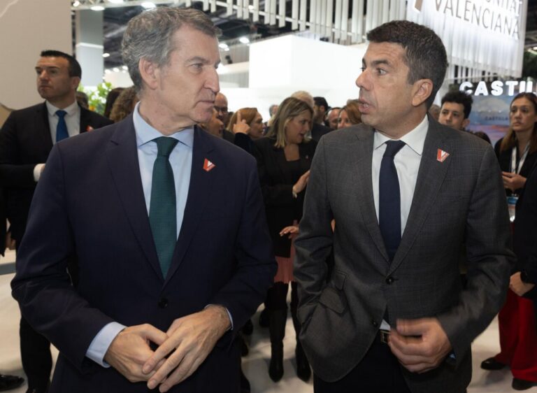 Alberto Núñez Feijóo conversando en un evento político con otro hombre.