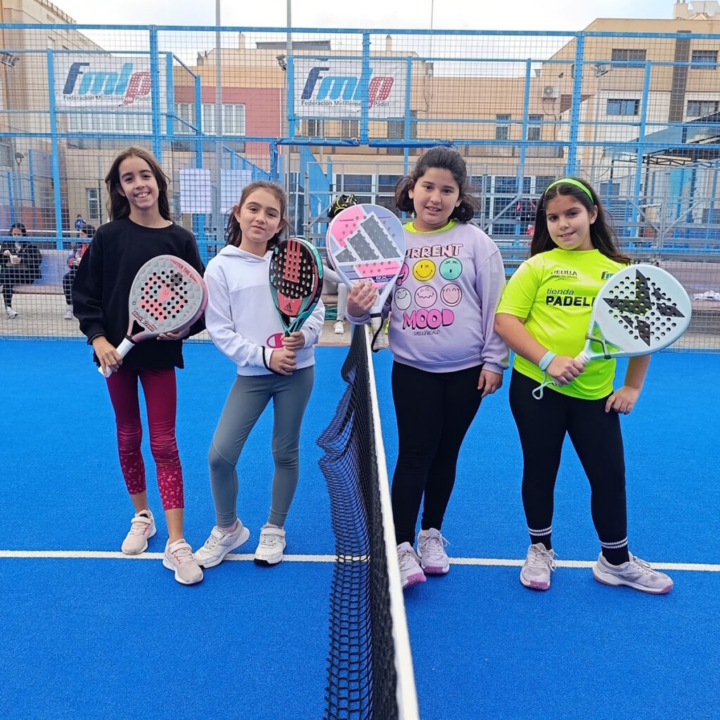 Cuatro jóvenes jugadoras de pádel posando en la cancha