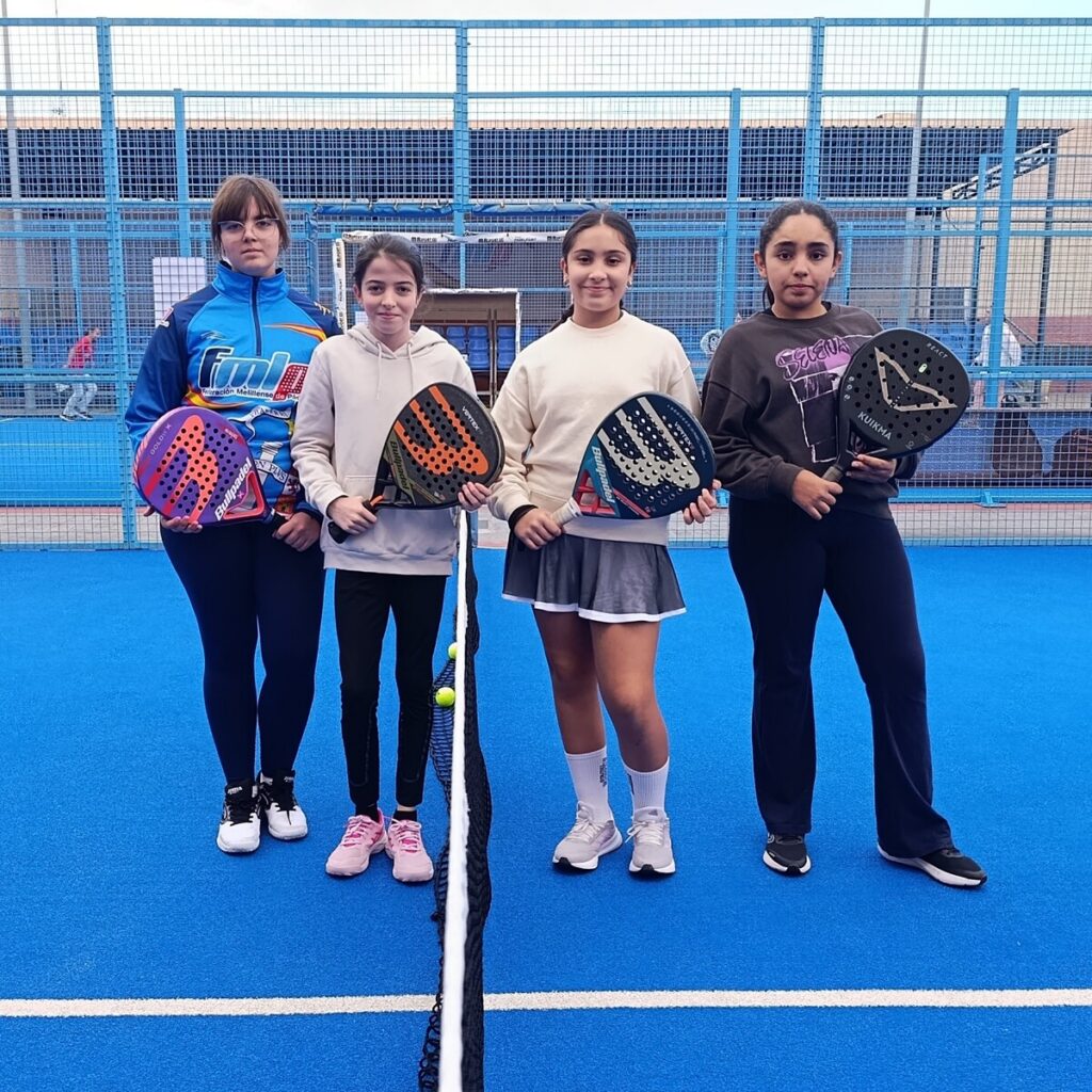 Cuatro jóvenes jugadoras de pádel posando en la cancha