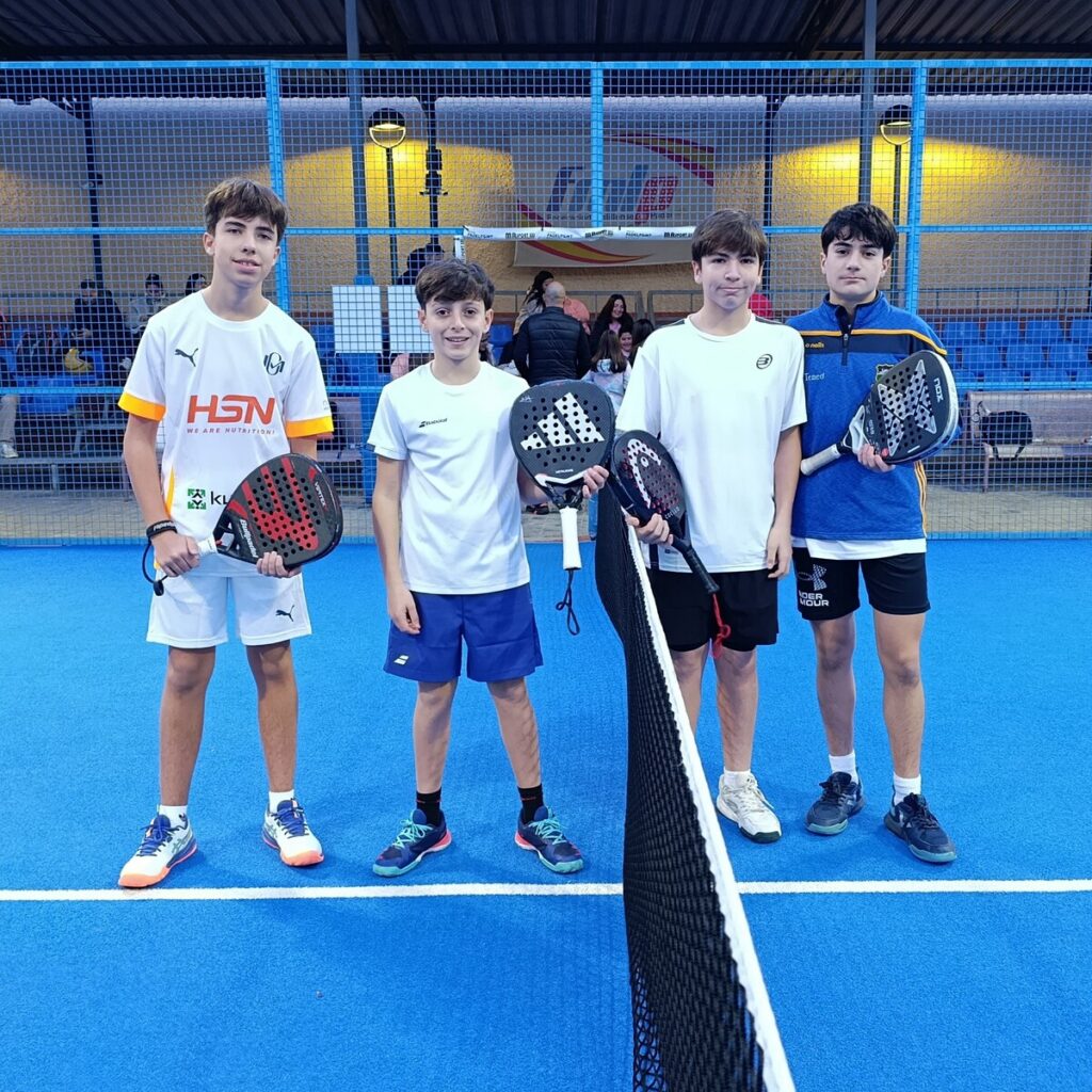 Cuatro jóvenes jugadores de pádel posando en la cancha