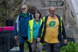 Tres personas caminando en un vivero durante una plantación solidaria