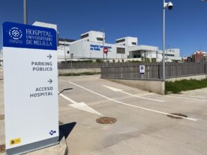 Señalización de acceso al Hospital Universitario de Melilla con parking público.