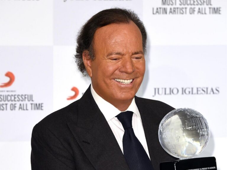 Julio Iglesias sonriendo mientras sostiene un premio en un evento