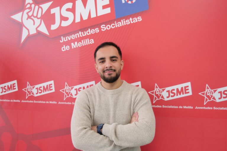 Miembro de Juventud Socialista de Melilla posando frente a un fondo rojo