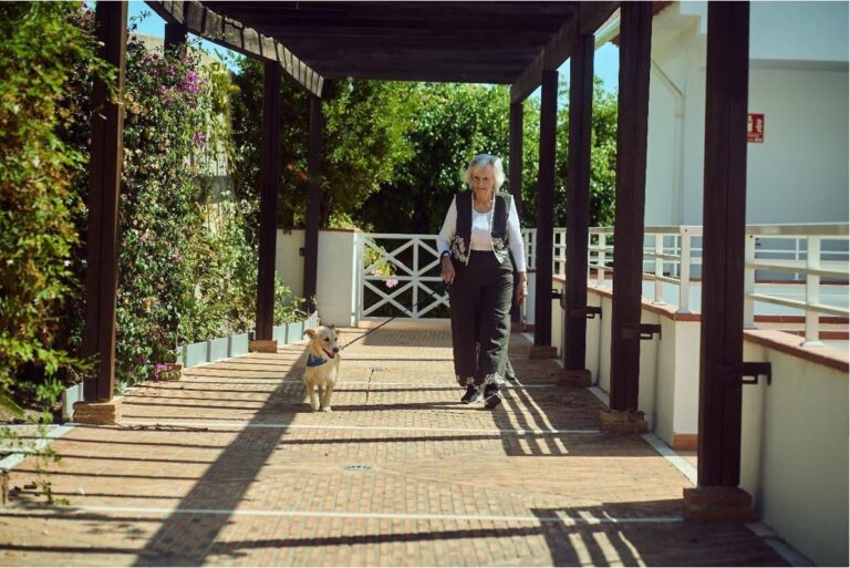 Una mujer mayor paseando con un perro en un entorno residencial