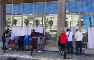 Grupo de personas observando a través de una ventana en la calle.