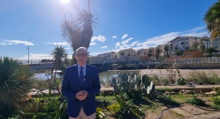 Hombre de pie frente a un paisaje en Melilla con cactus y edificios