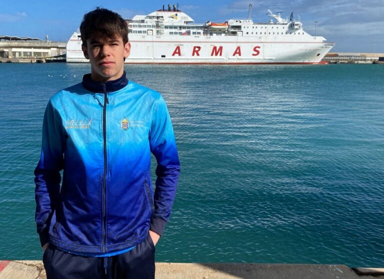 Pelayo Castaño posando junto al mar y un barco de Armas