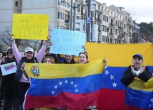 Manifestantes sosteniendo pancartas y banderas de Venezuela en una protesta.