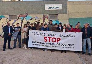 Grupo de personas sosteniendo una pancarta contra la violencia hacia docentes