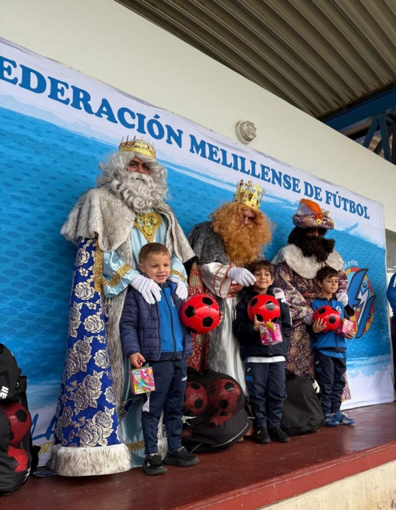 Los Reyes Magos con niños sosteniendo balones en un evento deportivo
