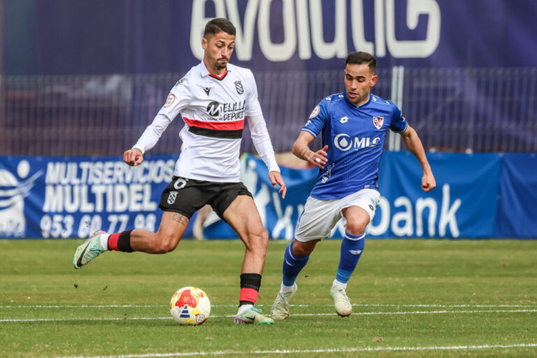 Jugadores de U.D. Melilla y Linares Deportivo en un partido de fútbol.