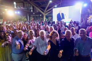 Grupo de personas mostrando el pulgar hacia arriba en un evento político.