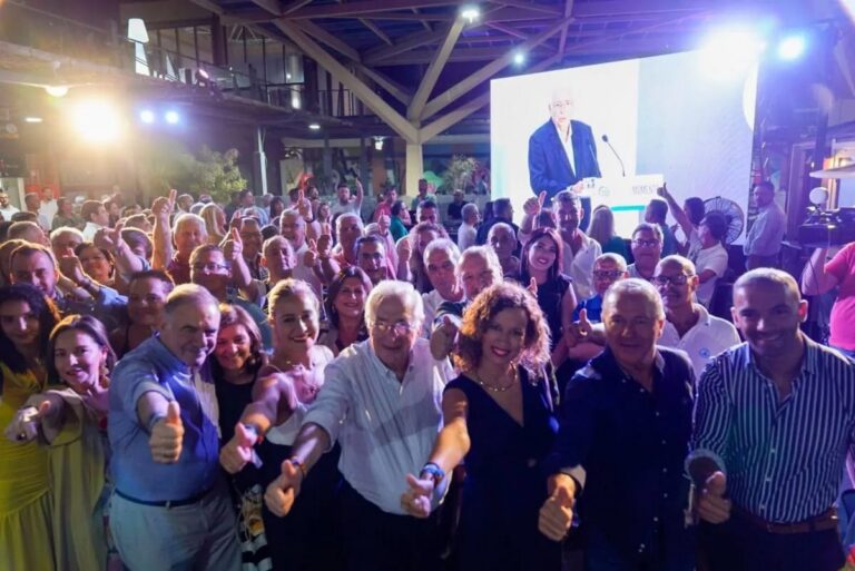 Grupo de personas mostrando el pulgar hacia arriba en un evento político.