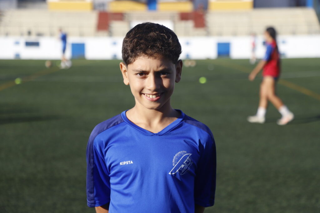 Niño sonriente en uniforme de fútbol en un campo de juego
