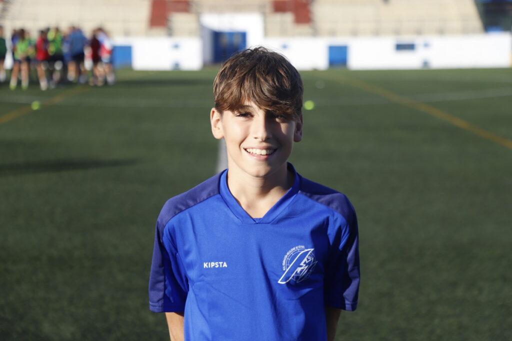 Niño sonriente en uniforme de fútbol en un campo deportivo