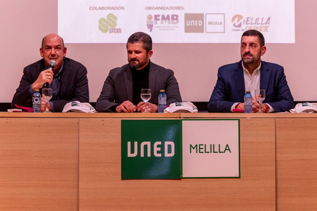 Tres hombres en una mesa durante la entrega de trofeos del torneo 3x3 UNED Melilla.