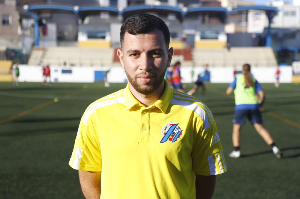 Entrenador de fútbol con camiseta amarilla en un campo de entrenamiento