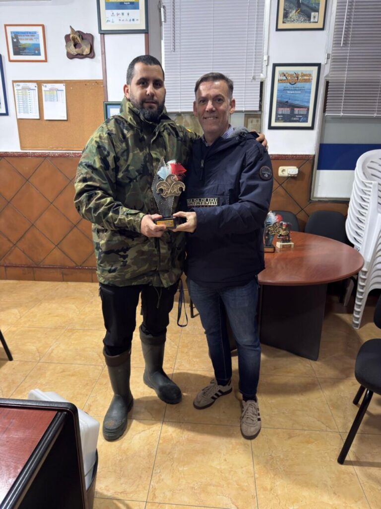 Carlos Javier Soler y otro hombre sosteniendo un trofeo en un evento de pesca