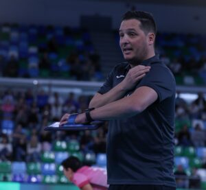 Entrenador Alberto Rodríguez dando instrucciones durante un partido de voleibol.