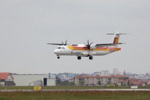 Avión aterrizando en un aeropuerto con edificios de fondo