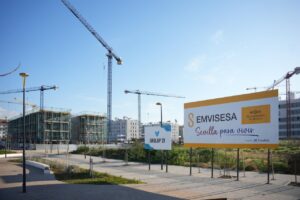 Construcción de viviendas en Sevilla con grúas y cartel de Emvisesa