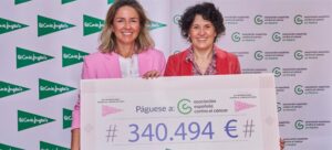 Mujeres sosteniendo un cheque de donación para la lucha contra el cáncer de mama.
