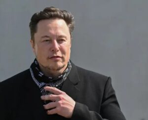 Elon Musk con un abrigo negro y una bufanda, en un evento público.