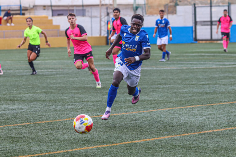 Jugador del filial de la U.D. Melilla corriendo con el balón en un partido