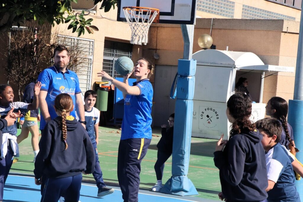 Grupo de niños y adultos jugando baloncesto en una cancha al aire libre