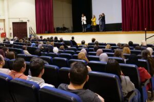 Una audiencia en un auditorio escuchando a los ponentes en el escenario
