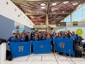 Grupo de personas en un aeropuerto sosteniendo banderas azules